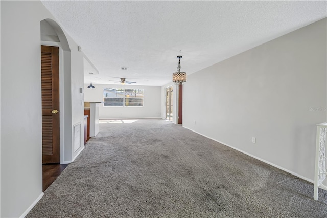 unfurnished living room with dark colored carpet, ceiling fan, and a textured ceiling