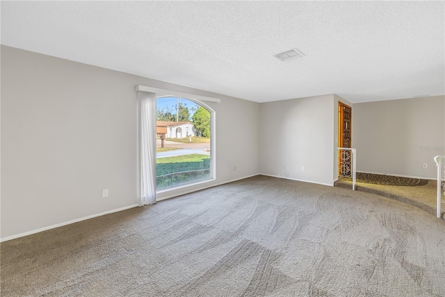 spare room with a textured ceiling and carpet flooring