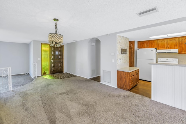 kitchen featuring hanging light fixtures, white fridge, dark carpet, and stove