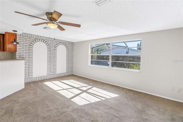 unfurnished living room with ceiling fan, a textured ceiling, and carpet