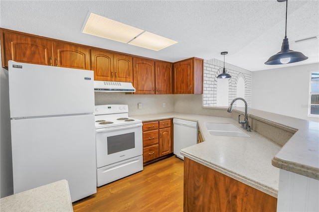 kitchen with sink, white appliances, light hardwood / wood-style flooring, a textured ceiling, and decorative light fixtures