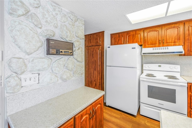 kitchen featuring extractor fan, white appliances, a textured ceiling, and light wood-type flooring