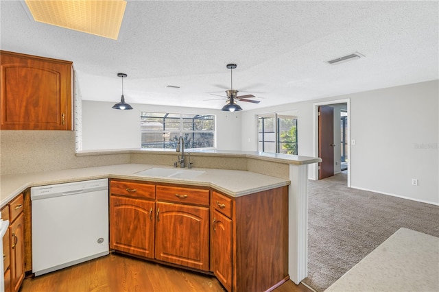 kitchen featuring pendant lighting, dishwasher, sink, ceiling fan, and kitchen peninsula