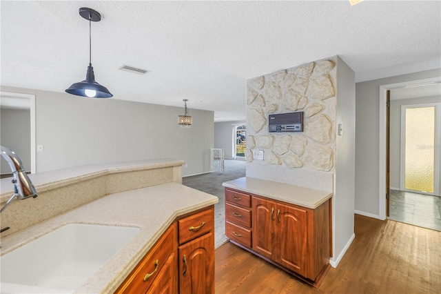 kitchen with sink, dark wood-type flooring, a textured ceiling, and decorative light fixtures