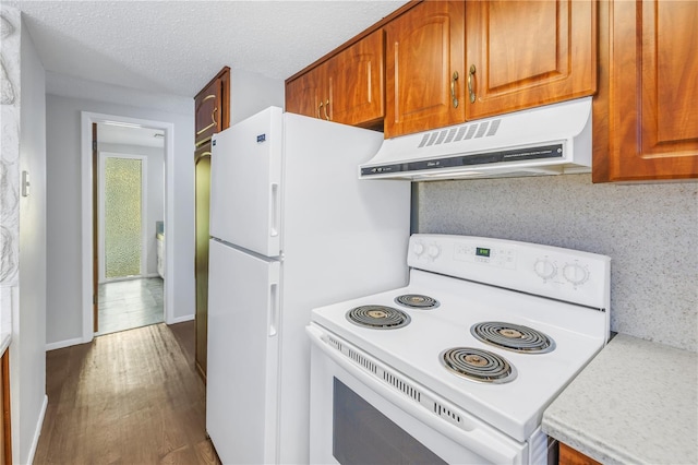 kitchen with hardwood / wood-style floors, white appliances, and a textured ceiling