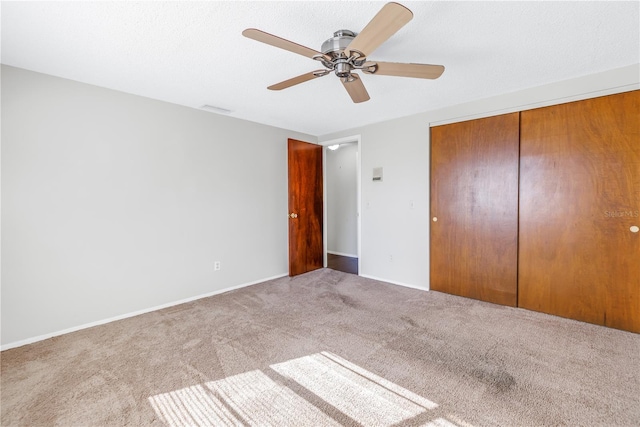 unfurnished bedroom featuring ceiling fan, carpet, a closet, and a textured ceiling