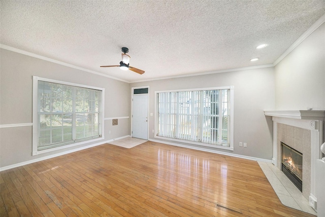 unfurnished living room featuring ceiling fan, light wood-type flooring, ornamental molding, and a tile fireplace