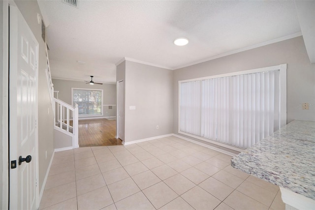 tiled empty room featuring ceiling fan, a textured ceiling, and ornamental molding