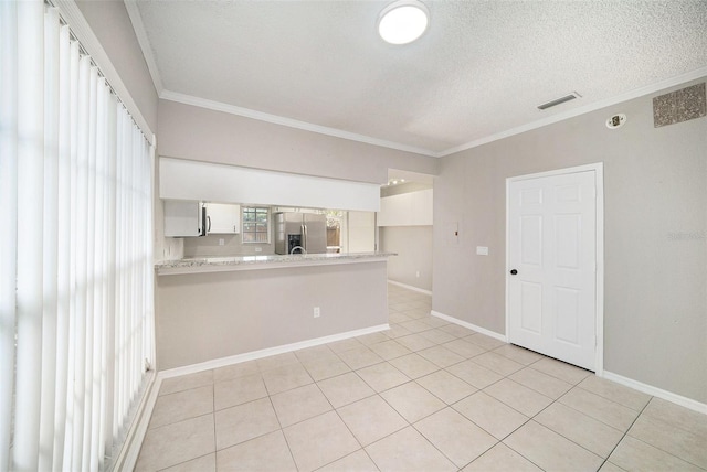 spare room featuring ornamental molding, a textured ceiling, and light tile patterned floors