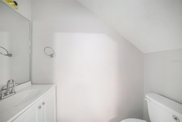 bathroom with vanity, vaulted ceiling, and toilet