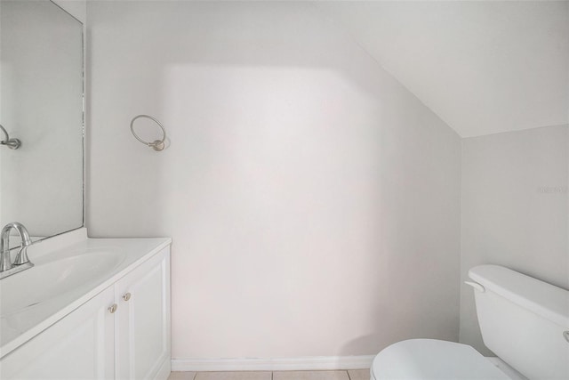 bathroom with toilet, vanity, vaulted ceiling, and tile patterned flooring