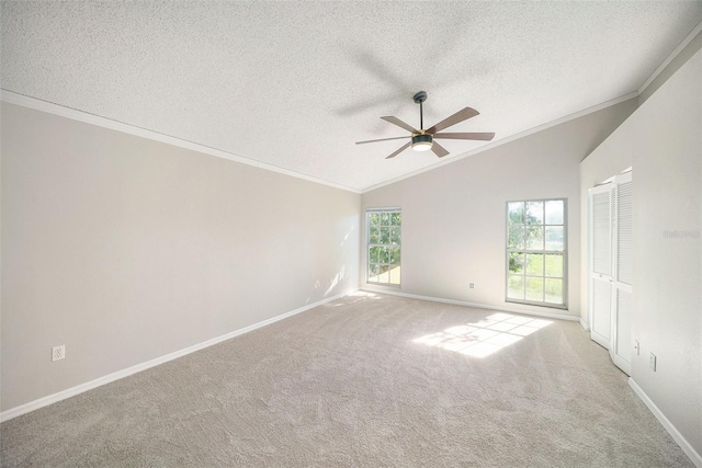 empty room with carpet flooring, crown molding, plenty of natural light, and vaulted ceiling