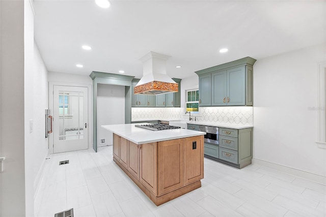 kitchen featuring a kitchen island, sink, decorative backsplash, island exhaust hood, and stainless steel gas cooktop