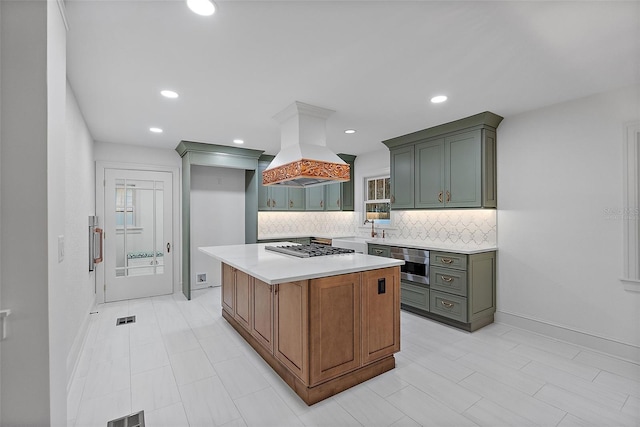 kitchen featuring stainless steel gas cooktop, sink, tasteful backsplash, island range hood, and a center island