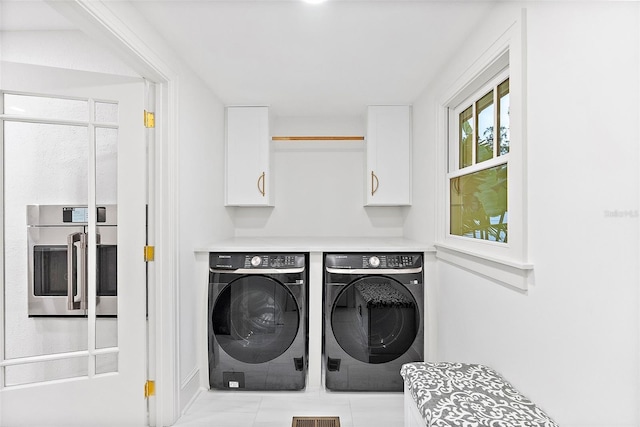 clothes washing area with cabinets and washer and dryer