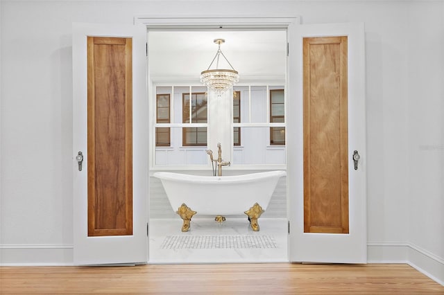 bathroom with a bathing tub, hardwood / wood-style floors, and a chandelier