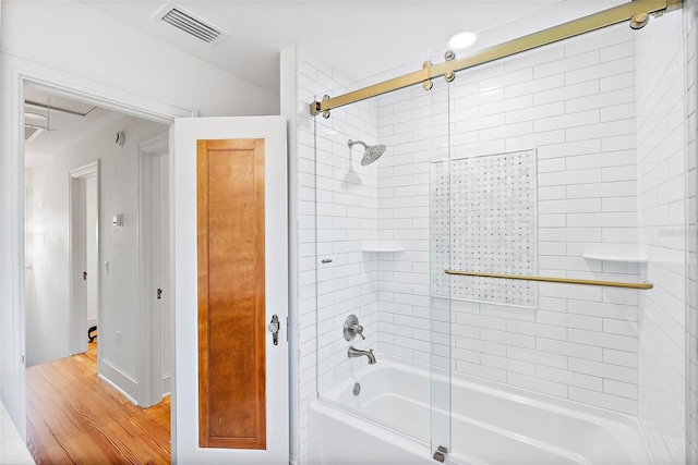 bathroom featuring wood-type flooring and shower / bath combination with glass door