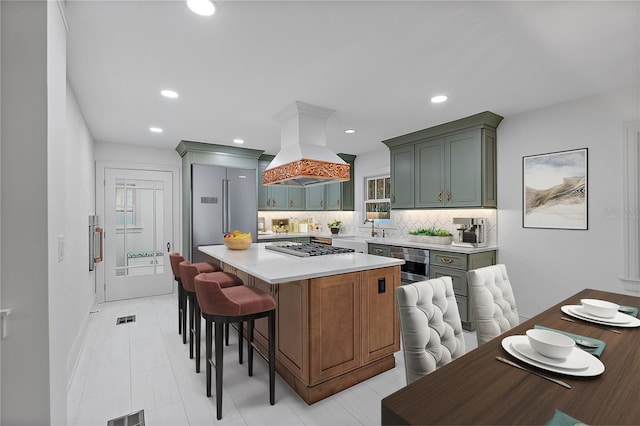 kitchen with premium range hood, a breakfast bar, tasteful backsplash, a center island, and appliances with stainless steel finishes