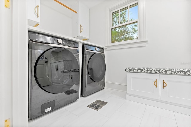 clothes washing area featuring cabinets and washing machine and dryer