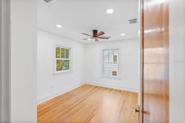 spare room featuring a healthy amount of sunlight, hardwood / wood-style floors, and ceiling fan