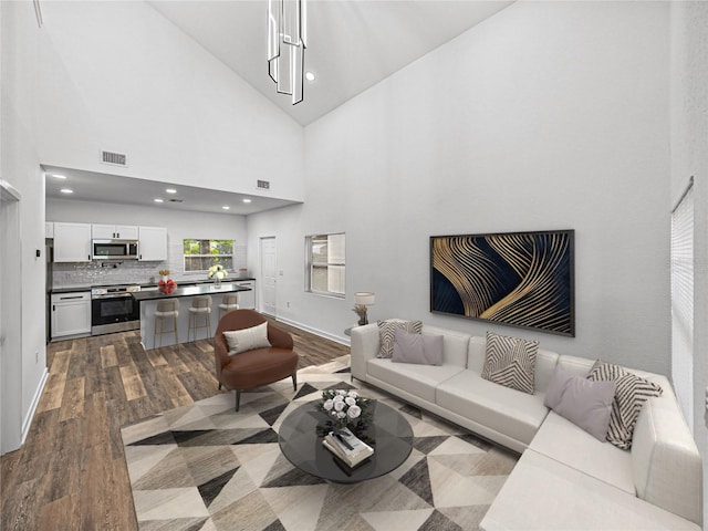 living room featuring light hardwood / wood-style flooring, high vaulted ceiling, and an inviting chandelier