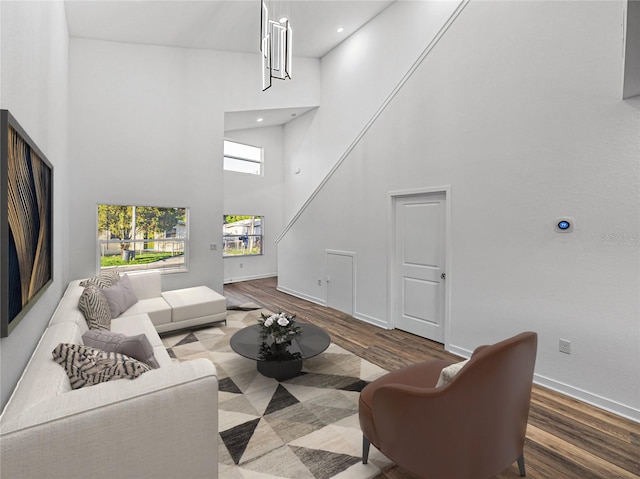 living room featuring hardwood / wood-style flooring, a towering ceiling, and a chandelier