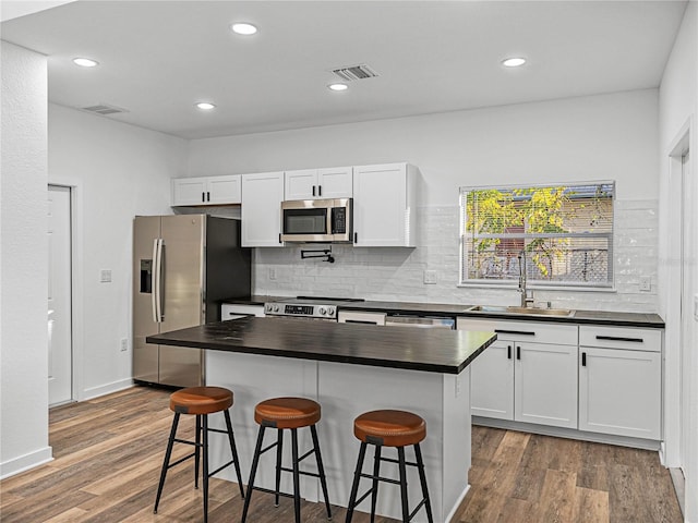 kitchen featuring a kitchen bar, sink, white cabinets, and appliances with stainless steel finishes