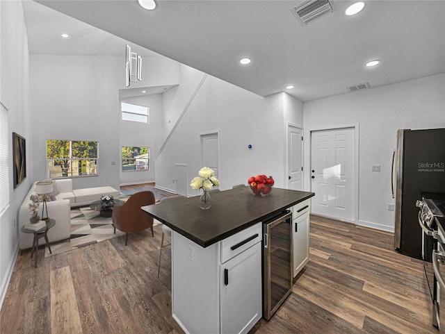 kitchen featuring appliances with stainless steel finishes, white cabinetry, beverage cooler, and dark wood-type flooring