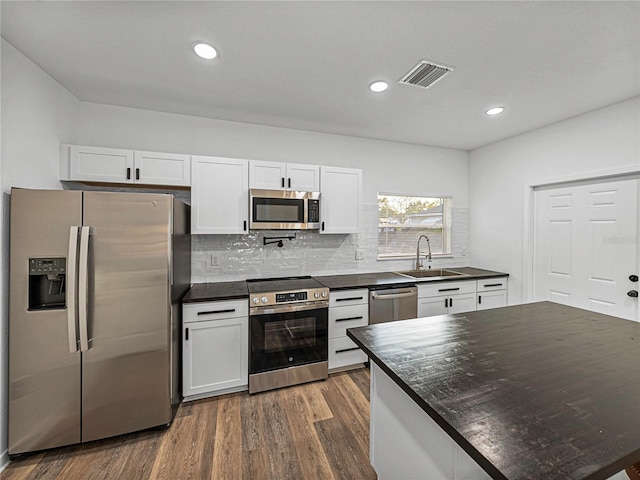 kitchen with decorative backsplash, appliances with stainless steel finishes, dark hardwood / wood-style flooring, sink, and white cabinets