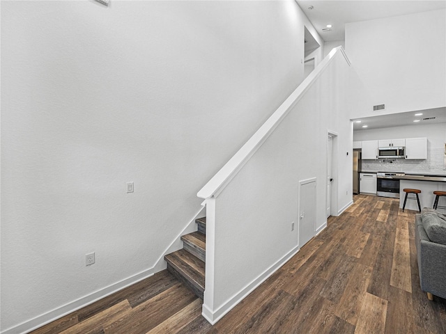 staircase with hardwood / wood-style floors and a high ceiling