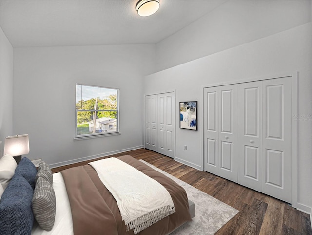 bedroom featuring multiple closets, dark wood-type flooring, and lofted ceiling