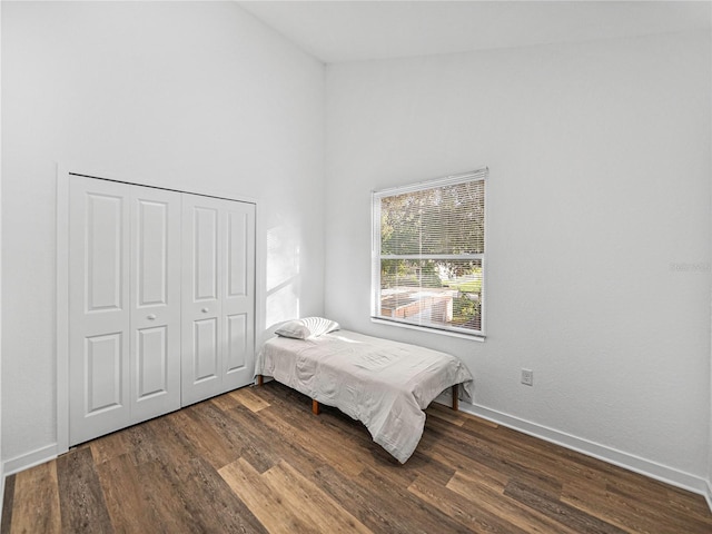 bedroom featuring a closet, dark hardwood / wood-style flooring, and lofted ceiling