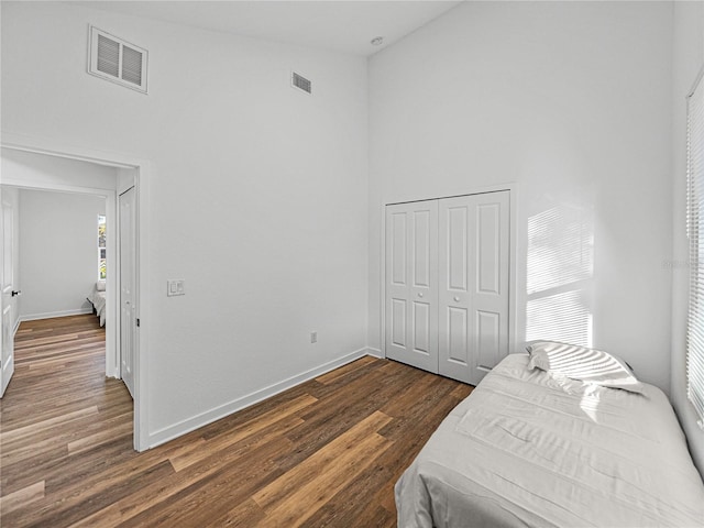 bedroom with a high ceiling, a closet, and dark wood-type flooring