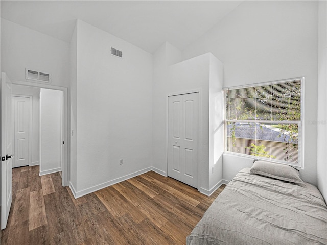 bedroom featuring a closet, high vaulted ceiling, and dark wood-type flooring