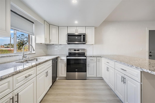 kitchen featuring light stone countertops, sink, appliances with stainless steel finishes, white cabinets, and light wood-type flooring