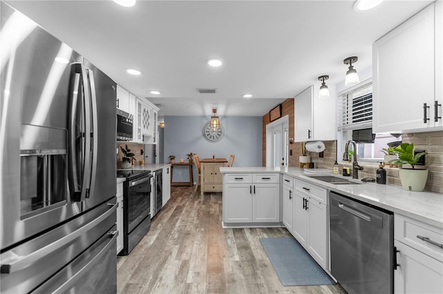 kitchen with white cabinetry, sink, stainless steel appliances, backsplash, and light wood-type flooring