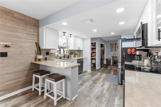 kitchen featuring a breakfast bar, stainless steel appliances, sink, light hardwood / wood-style flooring, and white cabinetry