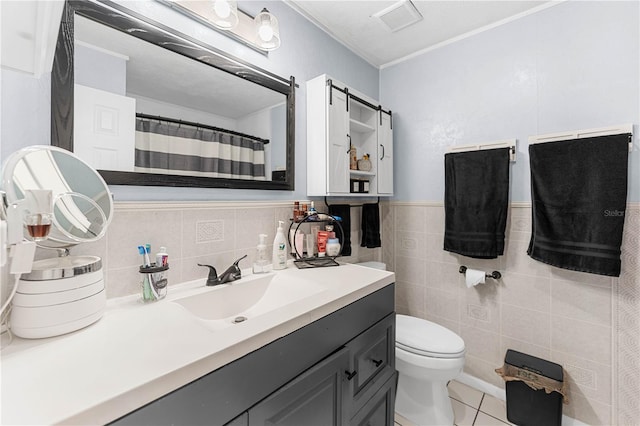 bathroom with tile patterned floors, vanity, tile walls, and toilet