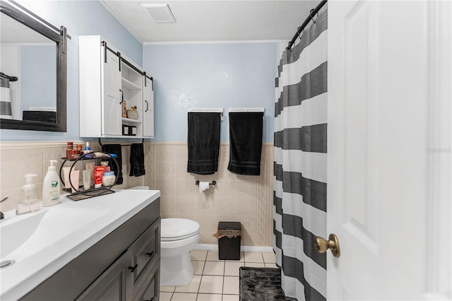 bathroom featuring vanity, tile patterned floors, toilet, tile walls, and a textured ceiling