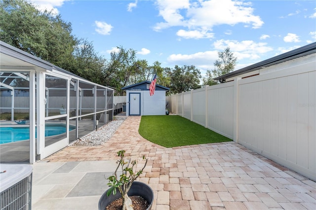 view of yard with a fenced in pool, glass enclosure, a storage shed, and a patio area