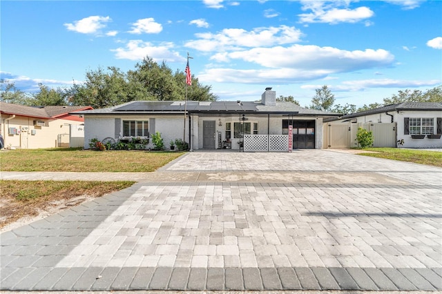 ranch-style house with solar panels, a porch, and a front yard