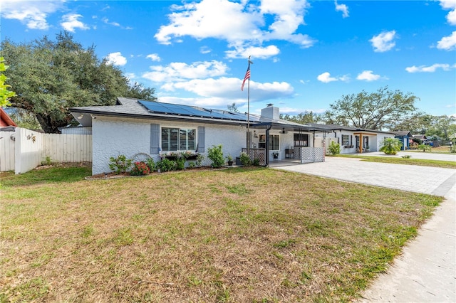 ranch-style house featuring a front yard and solar panels