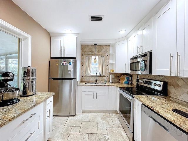 kitchen with white cabinetry, sink, stainless steel appliances, and decorative light fixtures