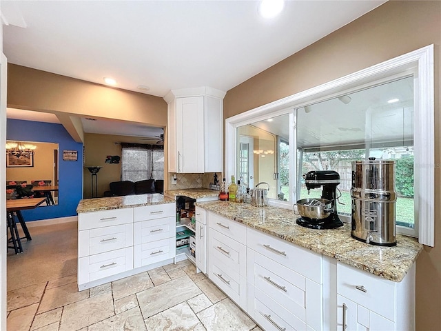 kitchen featuring white cabinets, ceiling fan, tasteful backsplash, light stone counters, and kitchen peninsula