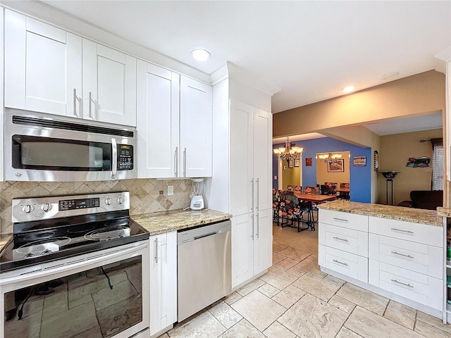 kitchen with decorative backsplash, white cabinetry, stainless steel appliances, and an inviting chandelier