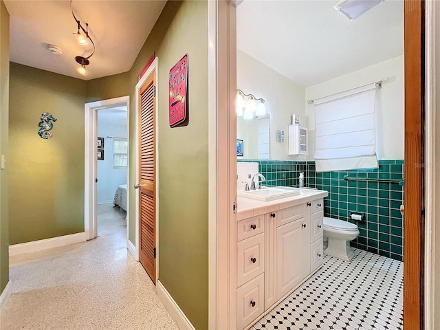 bathroom with vanity, toilet, and tile walls