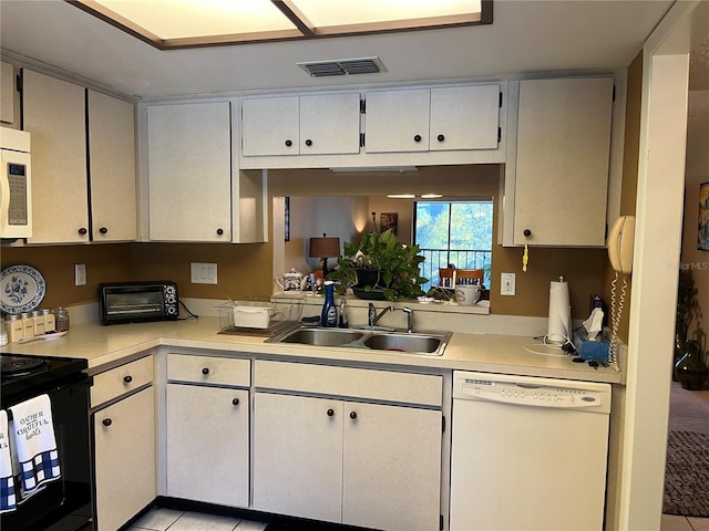 kitchen featuring white cabinetry, sink, light tile patterned flooring, and white appliances