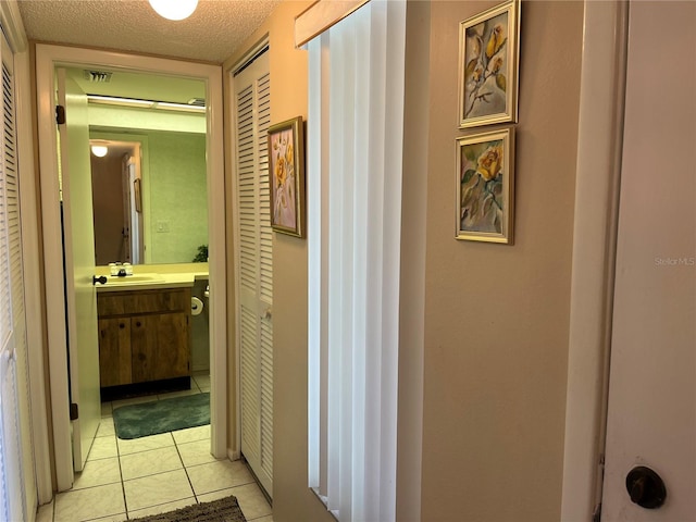 hallway featuring light tile patterned floors, a textured ceiling, and sink