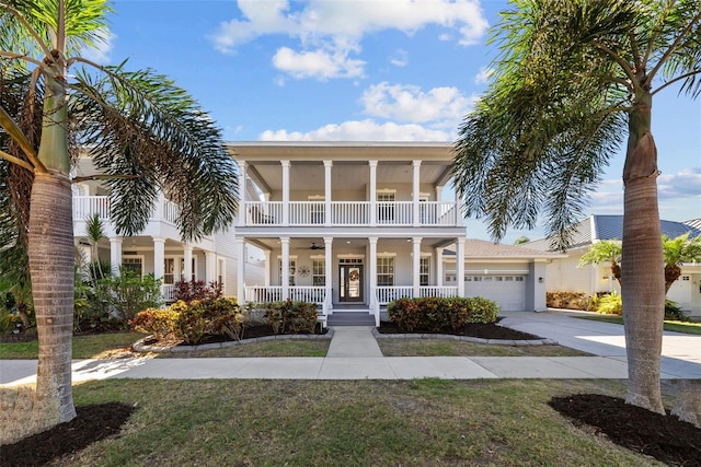 view of front of home with a balcony, covered porch, a garage, ceiling fan, and a front yard