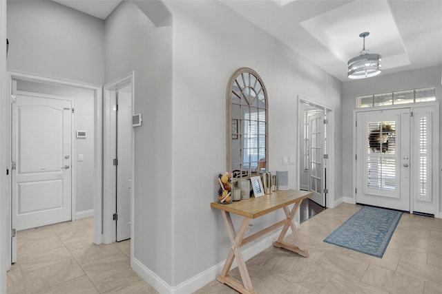 entryway with a raised ceiling and a chandelier